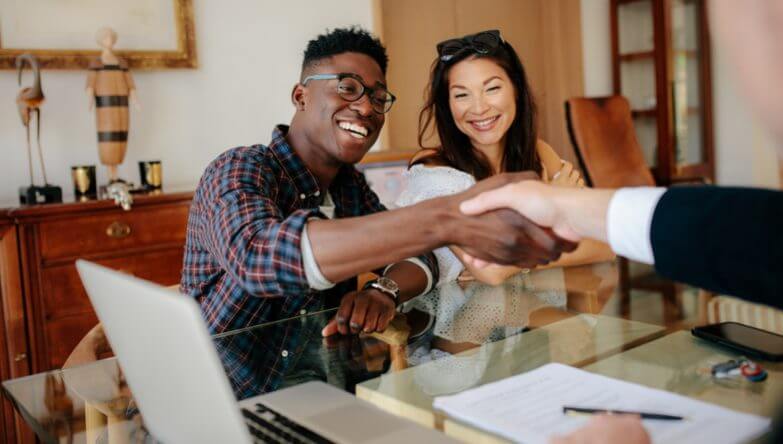 Couple shaking hands with cash buyers after they sell their house fast.